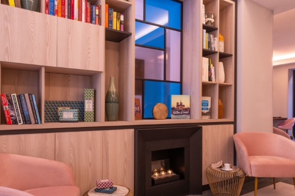 Hotel Le Milie Rose - a fireplace with books and a pink chair