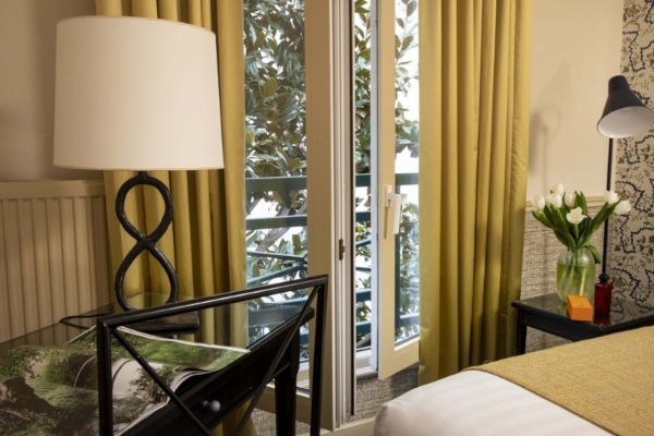 Hotel Relais Bosquet Paris by Malone - a bedroom with a glass door and a lamp