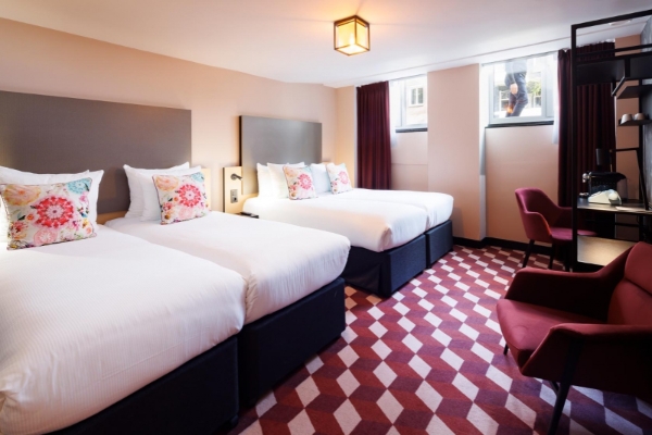 Krisotel - a room with two beds and a red and white patterned carpet