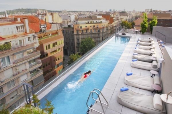 Ohla Eixample - a woman swimming in a pool with lounge chairs on top of it