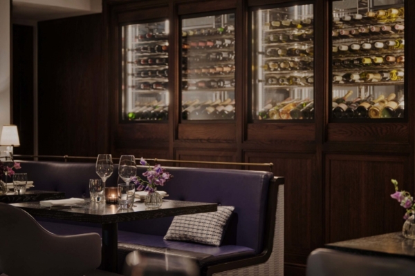 One Aldwych - a table with wine glasses and flowers in front of a wine rack