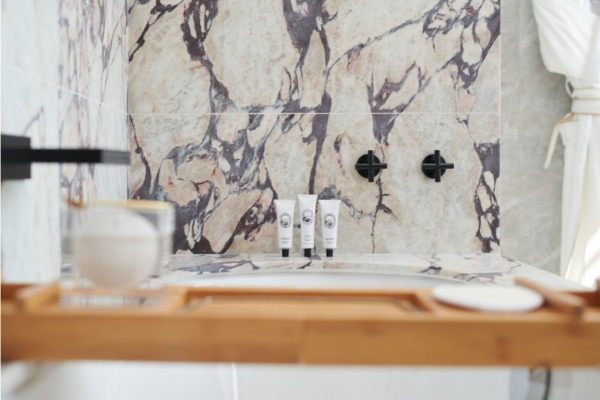 Pan Pacific London - a bathroom with a marble wall and a tub