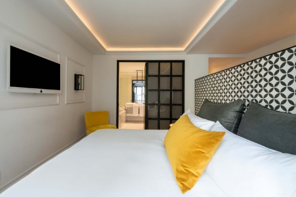 Serras Barcelona - a bed with yellow pillows and a black and white patterned headboard