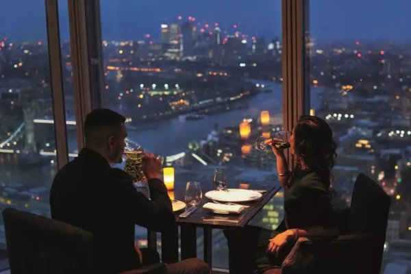 Shangri-La The Shard, London - a man and woman sitting at a table with drinks