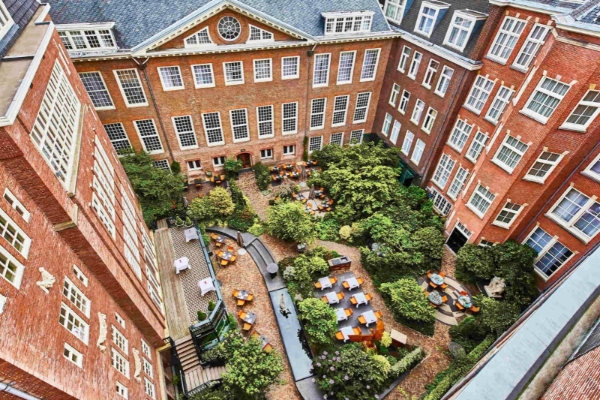 Sofitel Legend The Grand Amsterdam - a courtyard with trees and chairs in a building