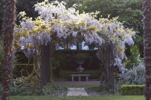 The Cadogan, A Belmond Hotel, London - a garden with a bench and a archway with purple flowers