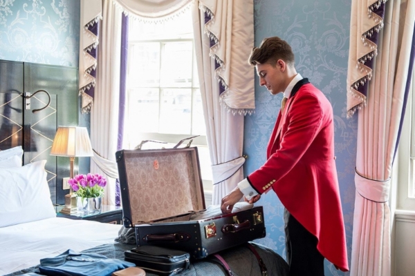 The Goring - a man in a suit opening a suitcase