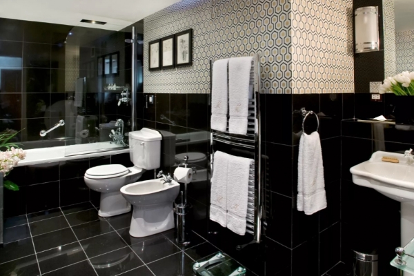 The Milestone Hotel and Residences - a bathroom with black tile walls and white towels