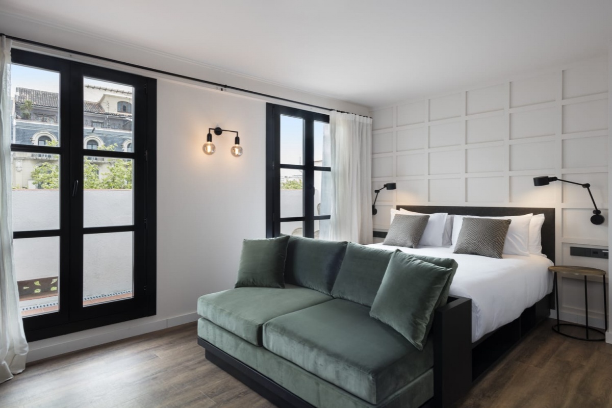 Yurbban Ramblas Boutique Hotel - a bedroom with a green couch and a black door
